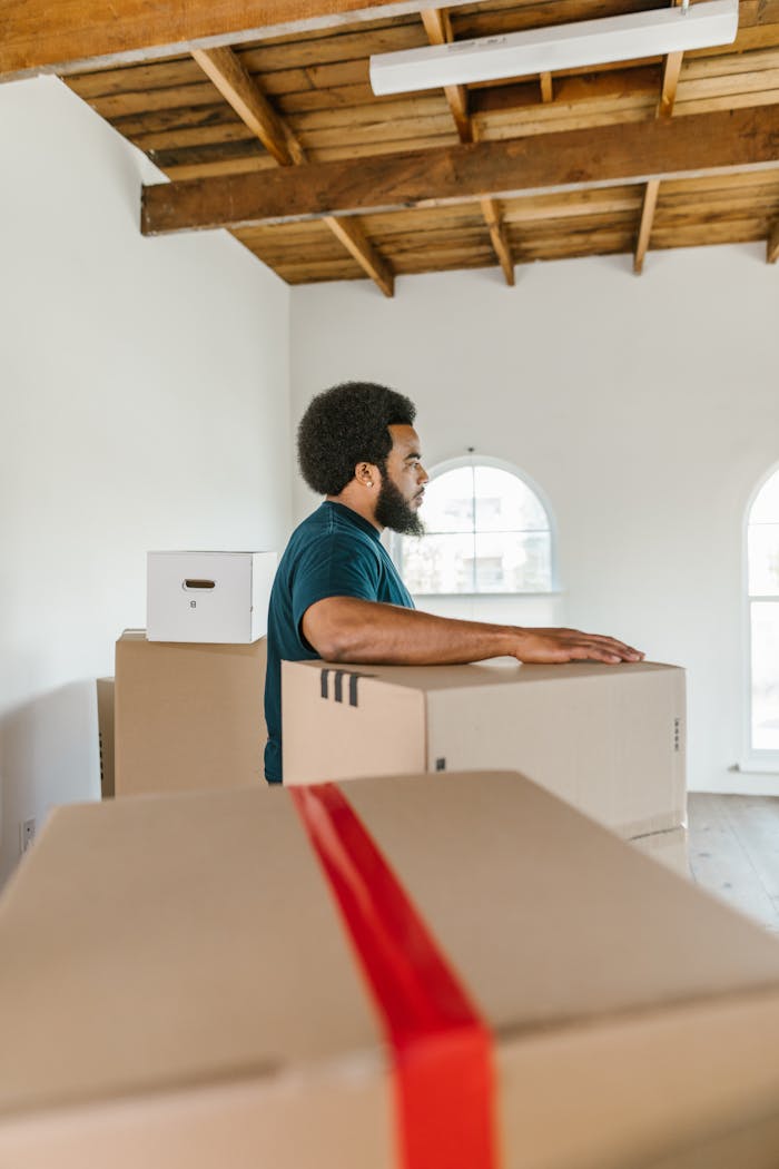 Man handling moving boxes in a spacious, modern room during relocation.